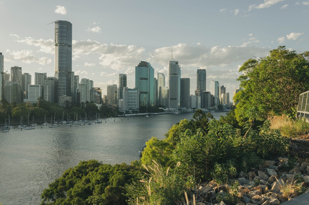 about-img-01 Stunning view of Brisbane's modern skyline and lush greenery by the river.