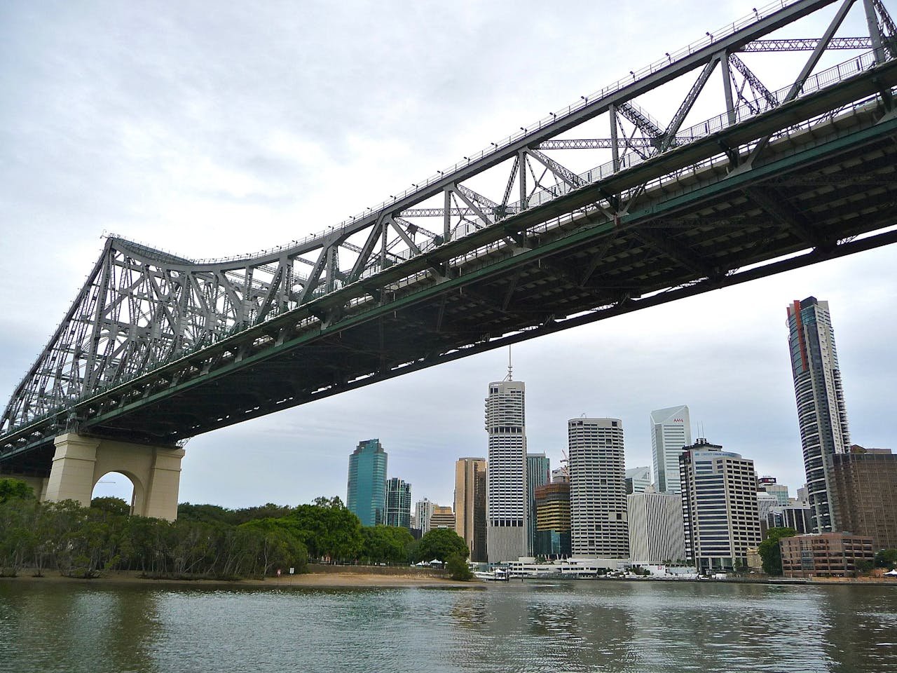 View of the Story Bridge over the Brisbane River with modern skyscrapers in the city skyline.